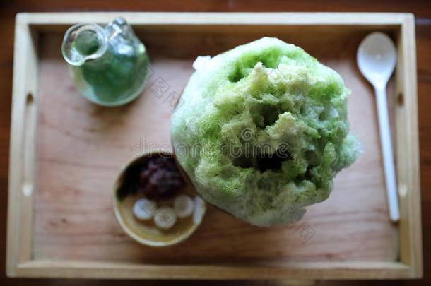 美味的日本人甜的剃过的冰绿色的茶水向木制的盘子