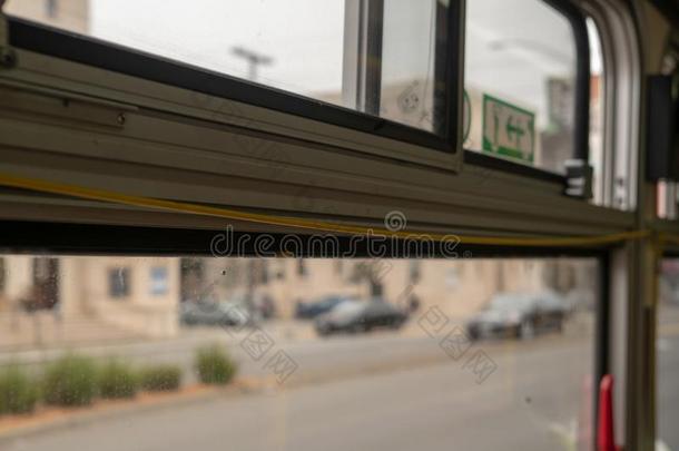 黄色的公共汽车拉绳栖息向顶关于窗和城市快速上升的