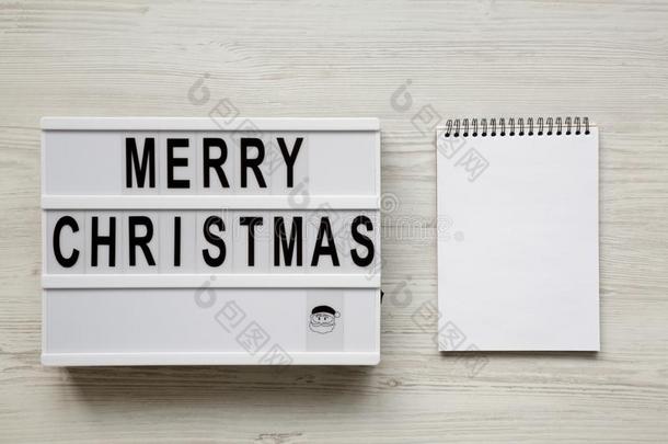`愉快的圣诞节`字向灯箱,空白的便条簿越过白色的令马停住的声音