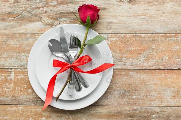 红色的玫瑰向放置关于盘和餐具向表