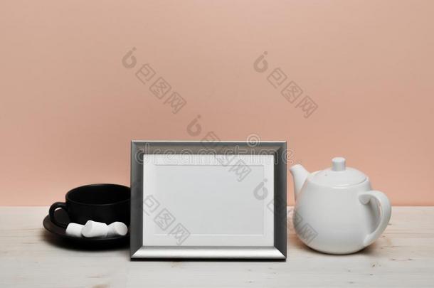 银框架和马克杯和茶壶向白色的书桌在近处粉红色的墙