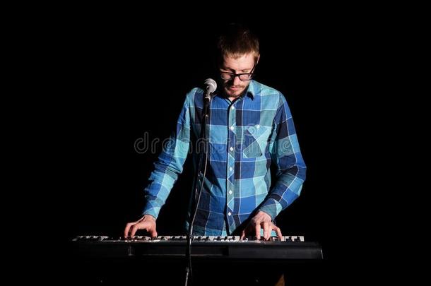 音乐家演奏键盘和音乐仪器向黑暗的后台