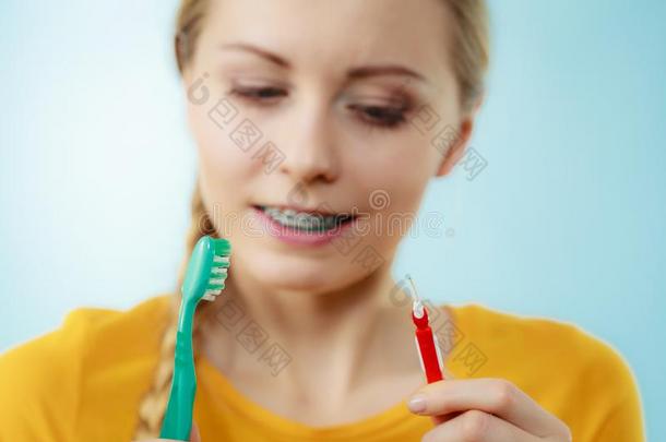 女孩和牙吊带使用牙齿之间的和传统的刷子
