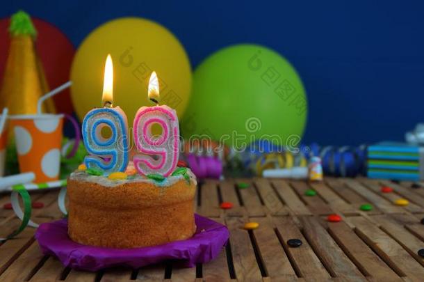 生日<strong>99</strong>蛋糕和蜡烛向乡村的木制的表和后面