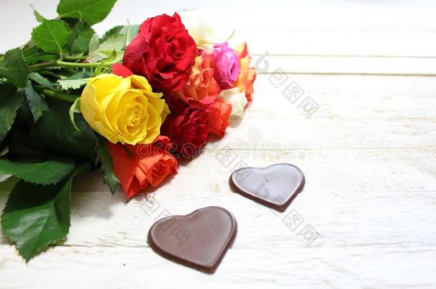 富有色彩的玫瑰和巧克力<strong>心</strong>向白色的木制的板