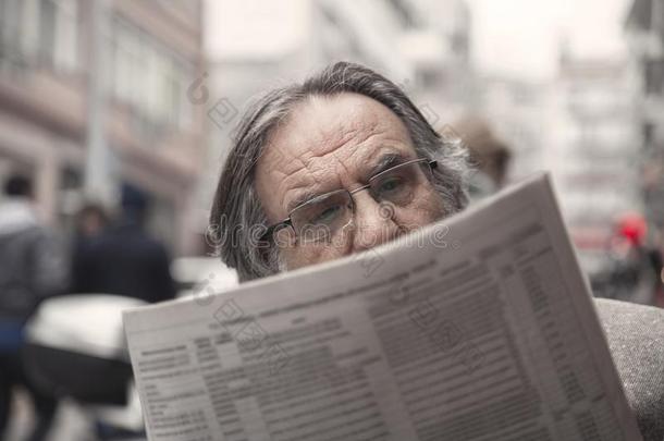 较高的男人阅读报纸采用在户外
