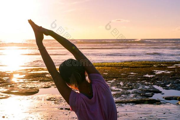 年幼的健康的女人开业的瑜伽向指已提到的人海滩在日落.