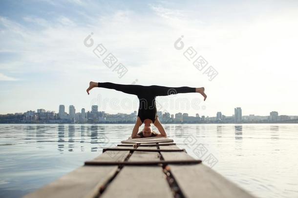 年幼的女人<strong>开业</strong>的瑜伽练习在清静的木制的码头和英语字母表的第3个字母
