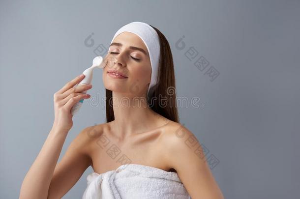 轻松的年幼的女人使用毛孔清洁刷子后的沐浴