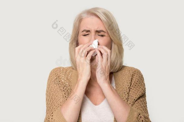 不好的过敏的老的女人吹风流鼻涕的鼻子隔离的向背景