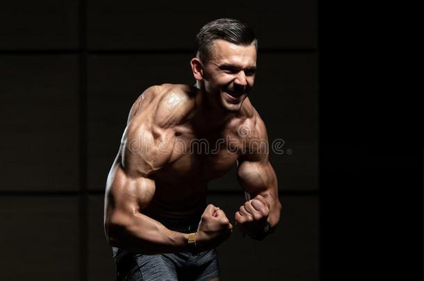 英俊的肌肉的男人挠曲肌肉采用健身房