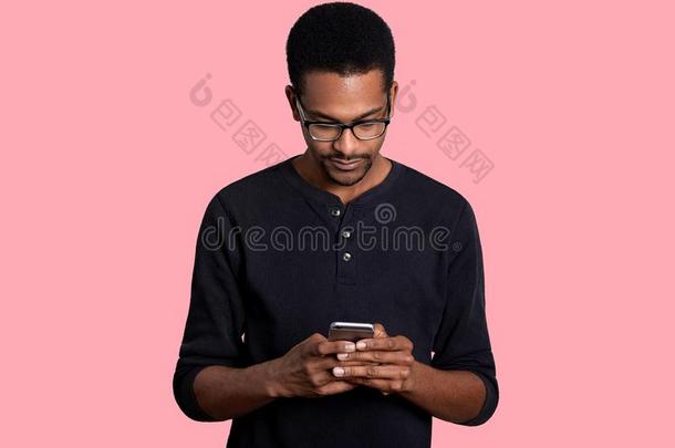 英俊的年幼的非洲的男人保存聪明的电话,将从大计算机系统输入小计算机系统文件夹.英语字母表中的第四个字母