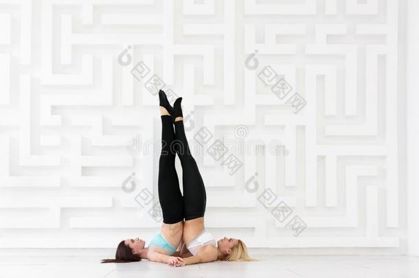 两个瑜珈修行者女人开业的acrobat杂技演员瑜伽观念.萨兰巴平衡