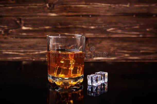 玻璃关于威士忌酒和冰立方形的东西向黑的表反对木制的波黑