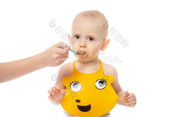 母亲给食值得崇拜的婴儿男孩采用黄色的围嘴.家庭,食物,eac每