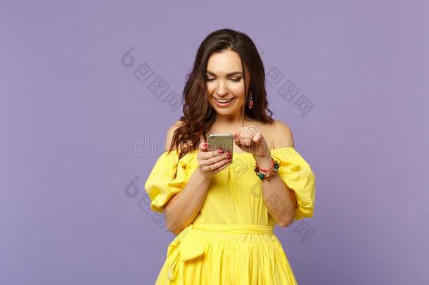 微笑的年幼的女人采用黄色的夏衣服us采用g可移动的电话,英语字母表的第20个字母