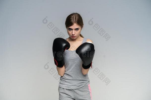女人拳击手采用拳击手套训练向灰色的背景.