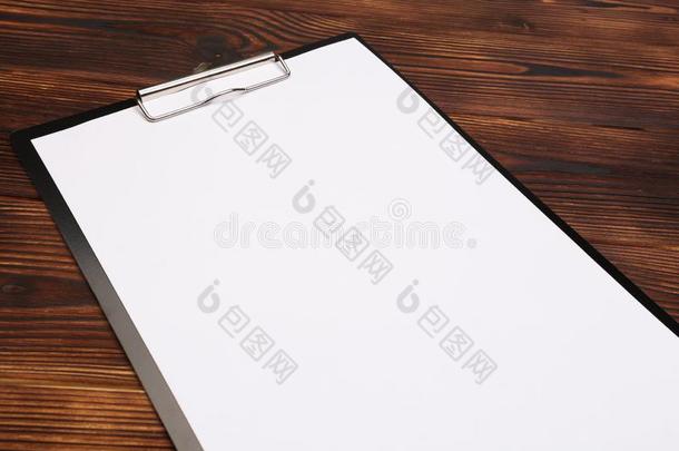 有纸夹的笔记板和白色的纸向木材背景.顶看法
