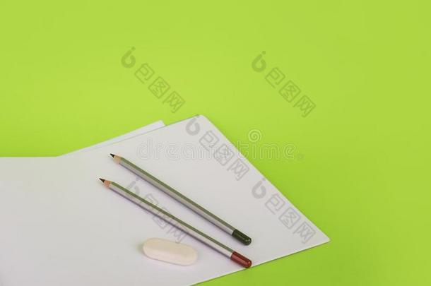 白色的纸和两个铅笔向一绿色的b一ckground.相册为dr一