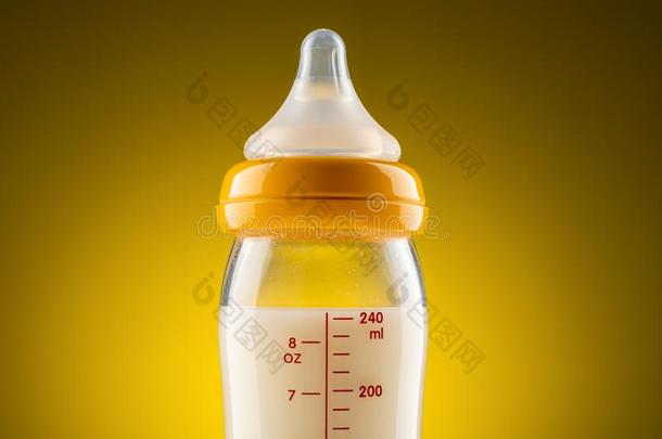 从背后照亮的玻璃婴儿瓶子和变成粉的奶特写镜头