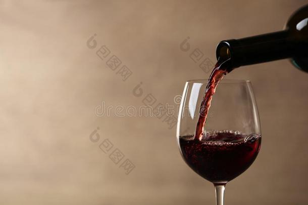 传布红色的葡萄酒进入中玻璃从瓶子反对blur红色的米黄色波黑