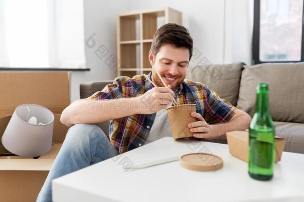 微笑的男人吃外卖餐馆食物在新的家