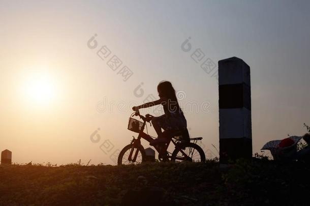 女儿是骑脚踏车兜风快乐地在日落