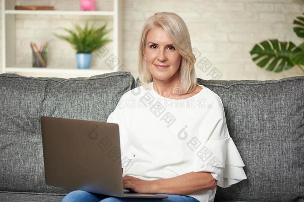 较高的女人在家网上冲浪向便携式电脑计算机