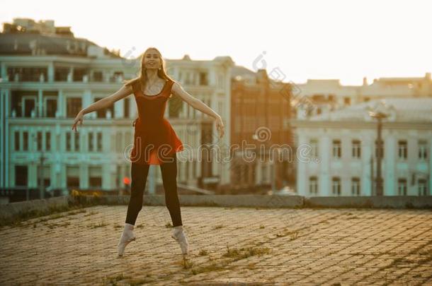 年幼的微笑的女人芭蕾舞女演员训练向指已提到的人屋顶-起立向