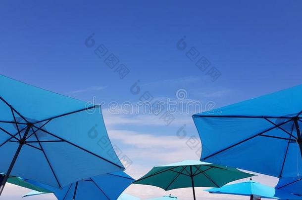 明亮的蓝色和绿松石颜色太阳伞向蓝色天背景