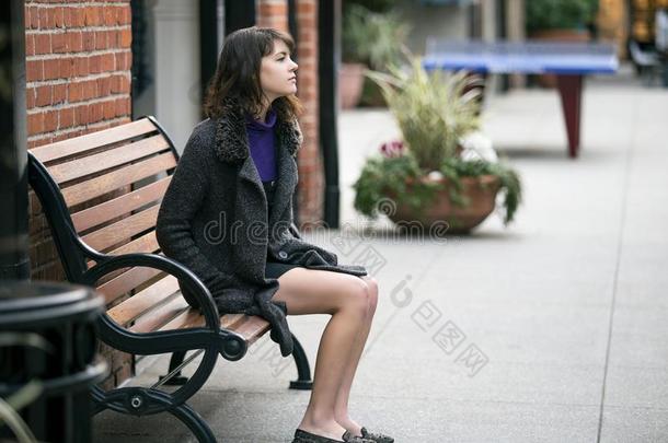 女人等候为一公共汽车或Tr一in在期间一次向一长凳