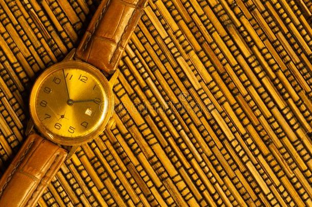 酿酒的金色的手表和皮用带捆扎向指已提到的人竹子后面