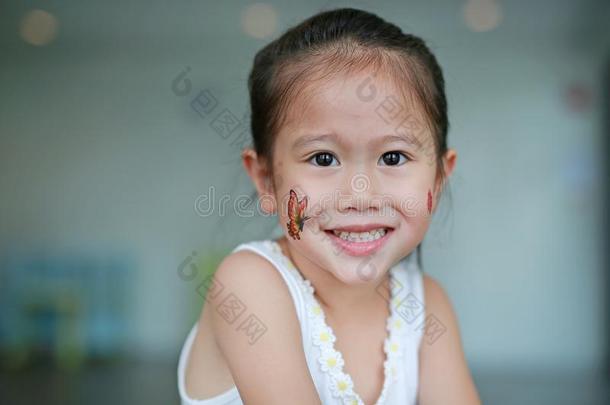 微笑的亚洲人小孩女孩和蝴蝶文身张贴物向脸