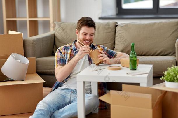 微笑的男人吃外卖餐馆食物在新的家