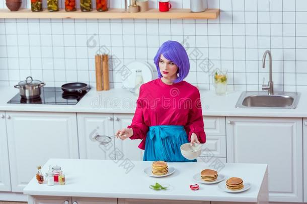 家庭主妇和紫色的头发和富有色彩的衣服烹饪术烙饼