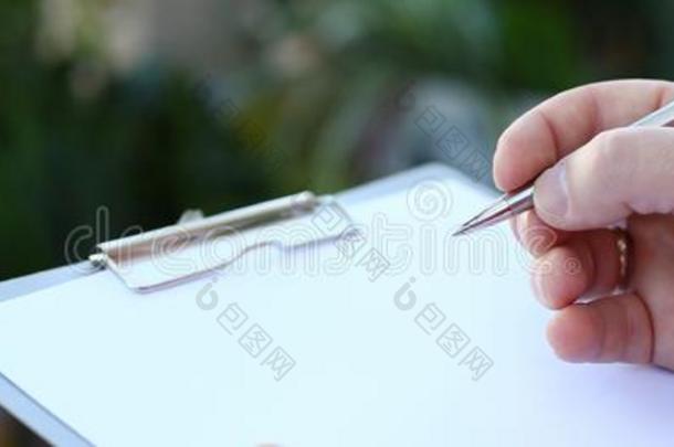 人手文字向有纸夹的笔记板和白色的纸