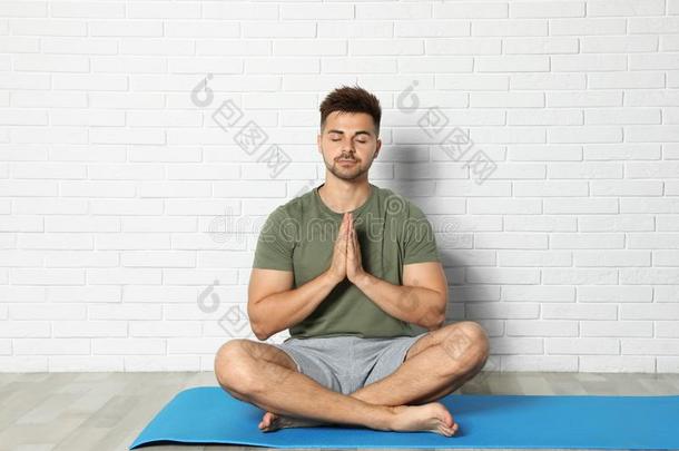 年幼的男人开业的禅瑜伽在近处砖墙