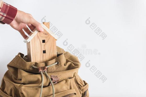 手拿小型的房屋模型采用指已提到的人棕色的颜色背包向wickets三柱门