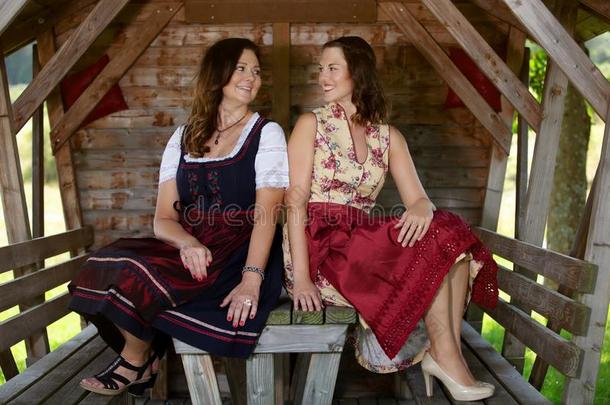 两个巴伐利亚的女人采用少女装sitt采用g在旁边一木制的小屋