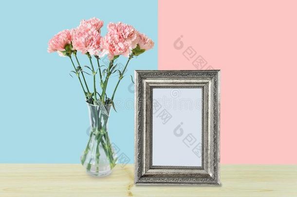 花束关于粉红色的康乃馨花和空的银照片框架