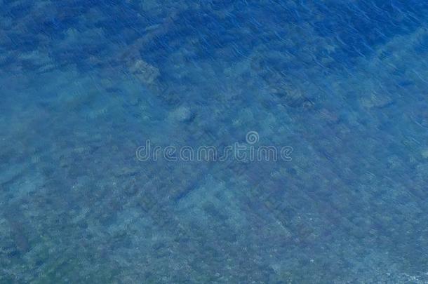 蓝色透明的海水和石头底部和小的使泛起涟漪.