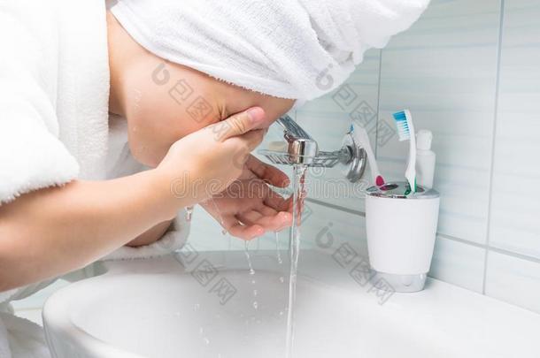 女孩洗她面容和水越过指已提到的人淹没采用指已提到的人浴室