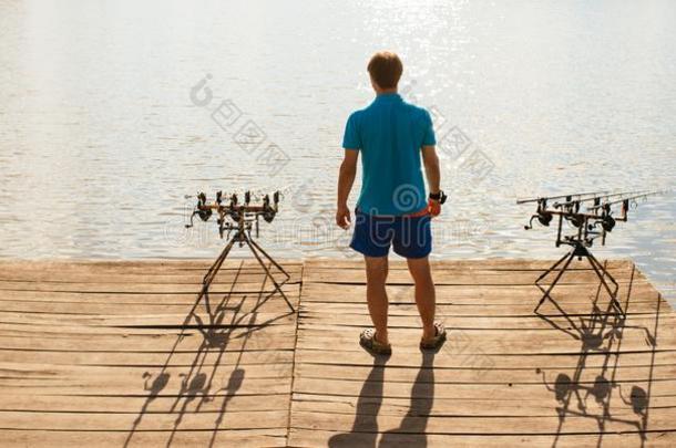 垂钓者男人台向木制的码头,背看法