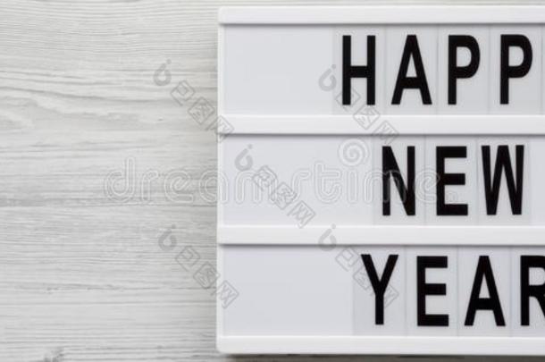 `幸福的新的年`字向一灯箱越过白色的木制的surf一ce,