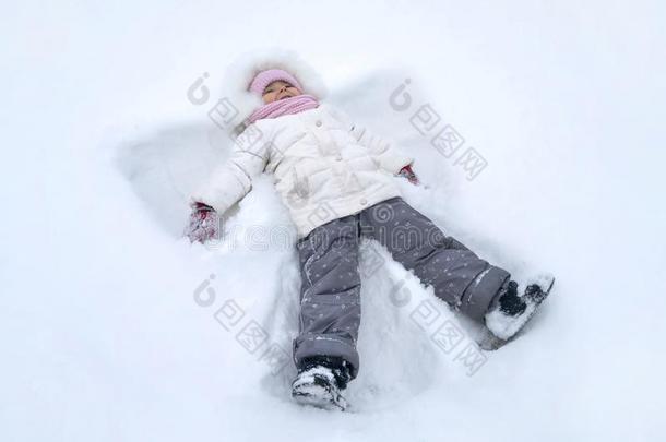 漂亮的女孩小孩使雪天使在冬公园