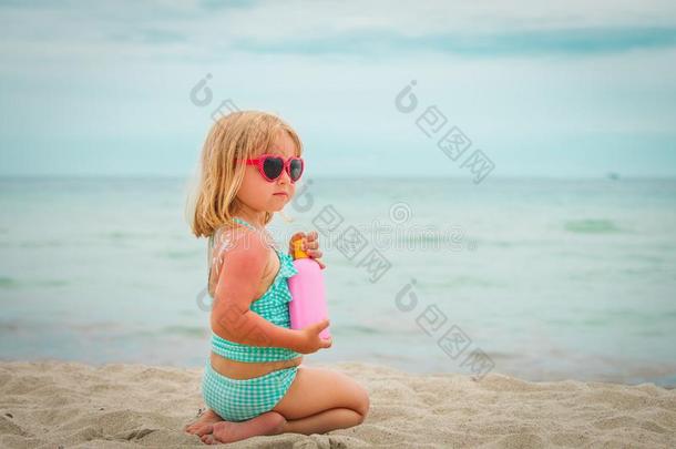 太阳保护观念-小的女孩和防晒霜在海滩