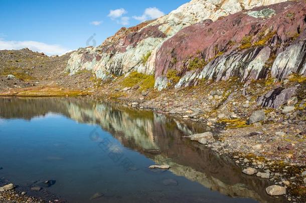 镇定的池塘反射的许多-有色的岩石关于红色的,紫色的和白色的