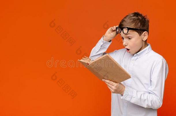 表现强烈情感的十几岁的青少年阅读使人兴奋的书,增加他的眼镜采用