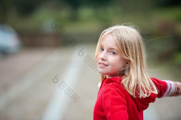 无忧无虑的年幼的白肤金发碧眼女人青春期前的女孩打扮好的采用红色的和模糊的波黑