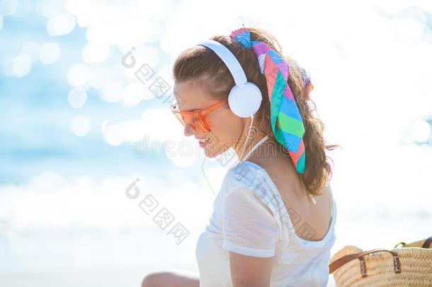 轻松的年幼的女人收听的向音乐向洋海岸